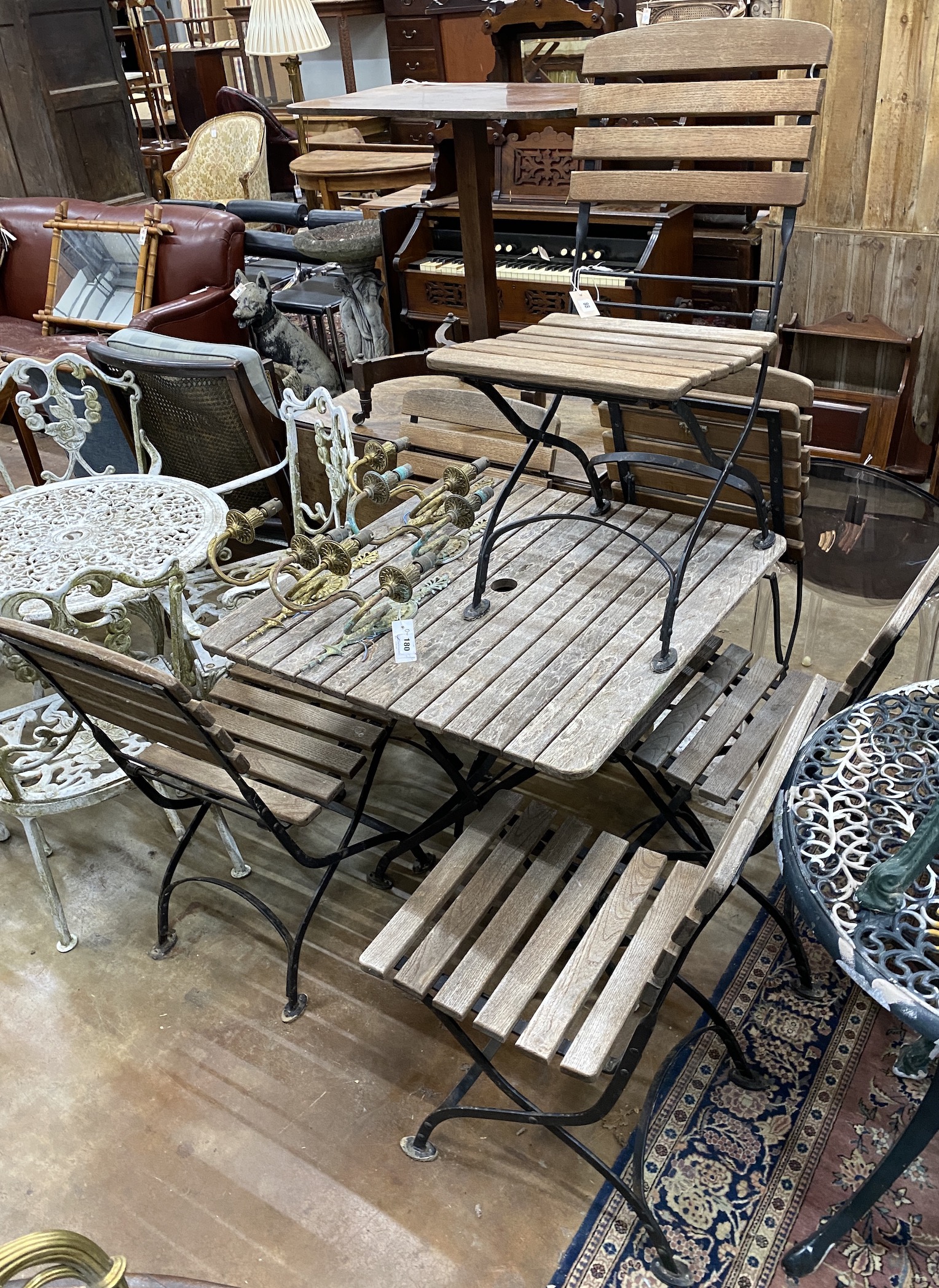 A square slatted teak and wrought iron folding garden table, width 80cm, height 73cm, and six folding chairs